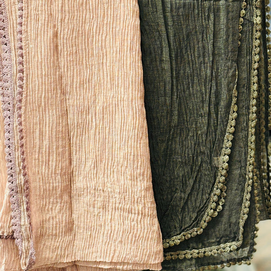 Two textured scarves, one beige and one green with decorative trim, draped over a surface.