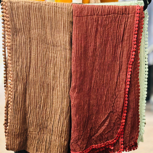 Two textured scarves, one brown and one red, hanging on a rack.