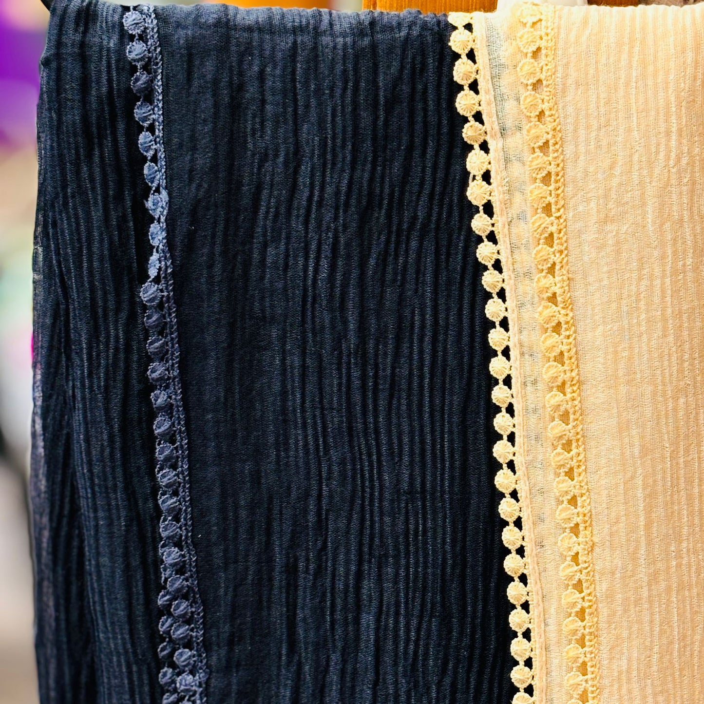 Close-up of dark blue and beige fabric with decorative trim, possibly from a garment.