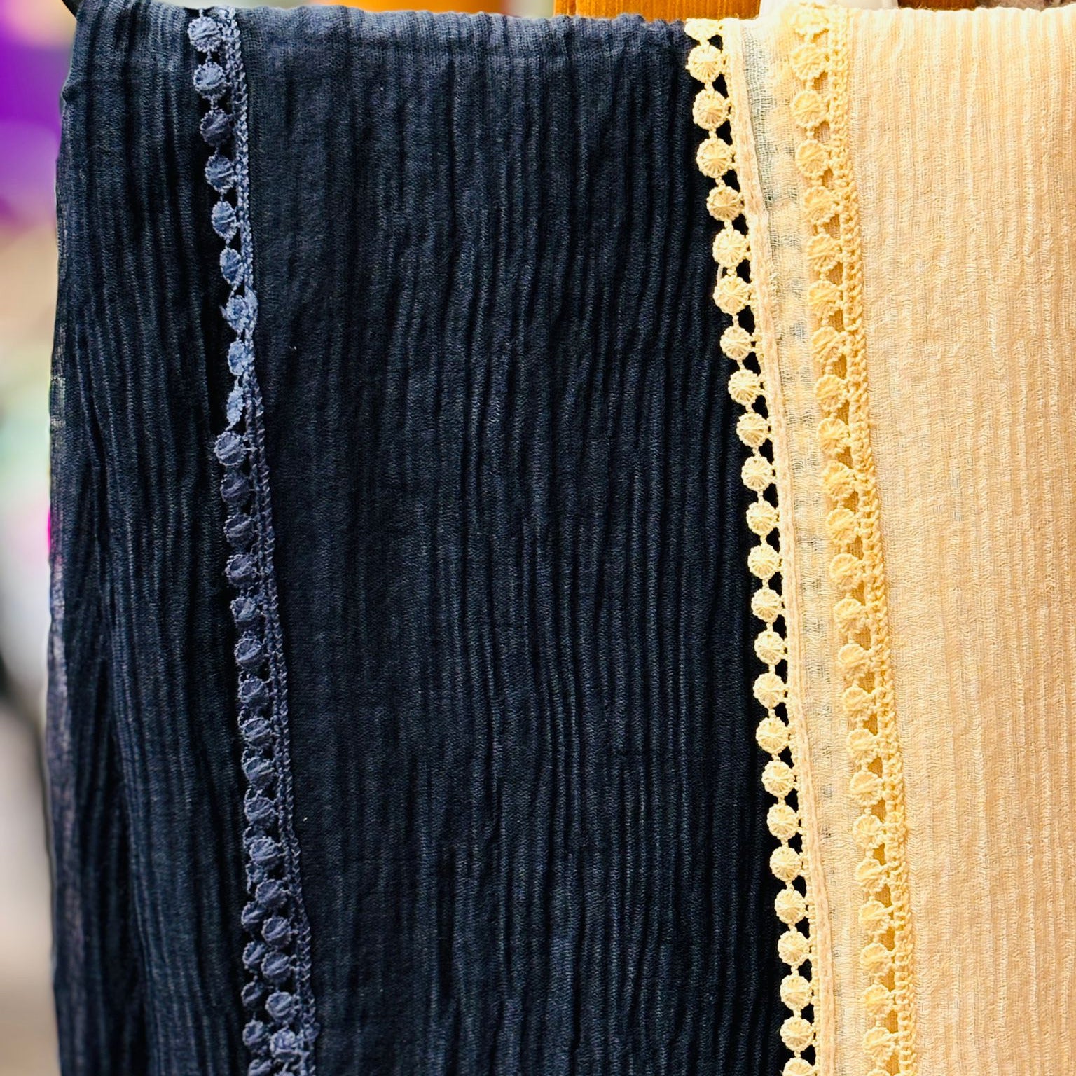 Close-up of dark blue and beige fabric with decorative trim, possibly from a garment.